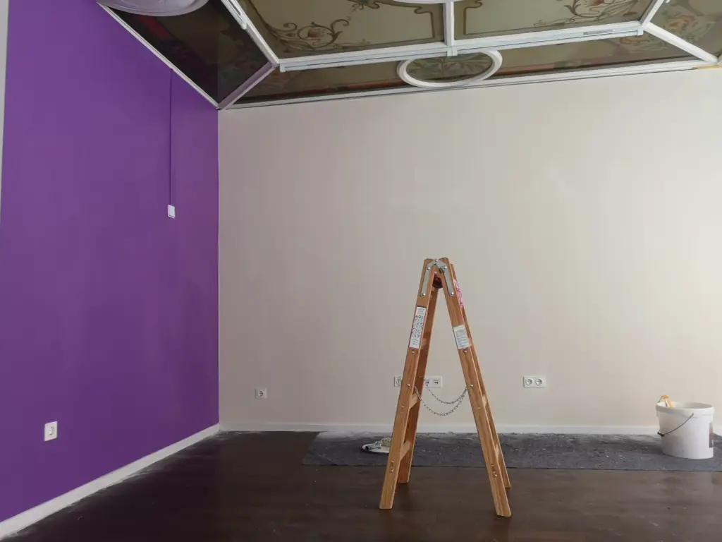 Das Bild entstand während der Malerarbeiten, man sieht Farbeimer und Leiter vor fertig gestrichener lila und beiger Wand.